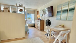 Ein geräumiger Wohnbereich mit Esstisch, einer Couch, einer Küchenzeile mit Kühlschrank und Blick auf den Balkon.