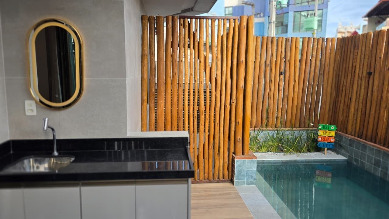 A bathroom with a sink, mirror, and a bamboo partition.