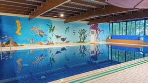 An indoor swimming pool with a mural of marine life, a diving board, and a bench. - Ewijk Lake Bungalow With Garden (Ewijk)