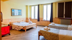 Une chambre avec deux lits, une fenêtre avec des rideaux, un radiateur et un tableau au mur.