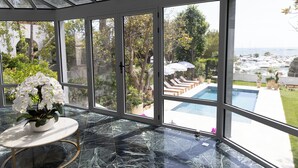 Um solário com vista para a piscina, chão de mármore e flores brancas.