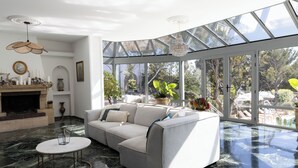Uma sala de estar moderna com um sofá branco, teto de vidro e lareira.