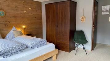 Un dormitorio con una cama de madera, un armario, una silla verde y una pared decorada con corazones.