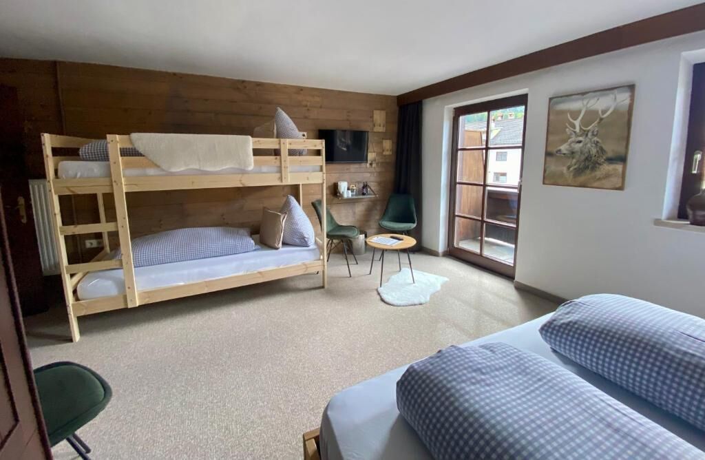 Una habitación con literas, una mesita, una silla y un televisor.
