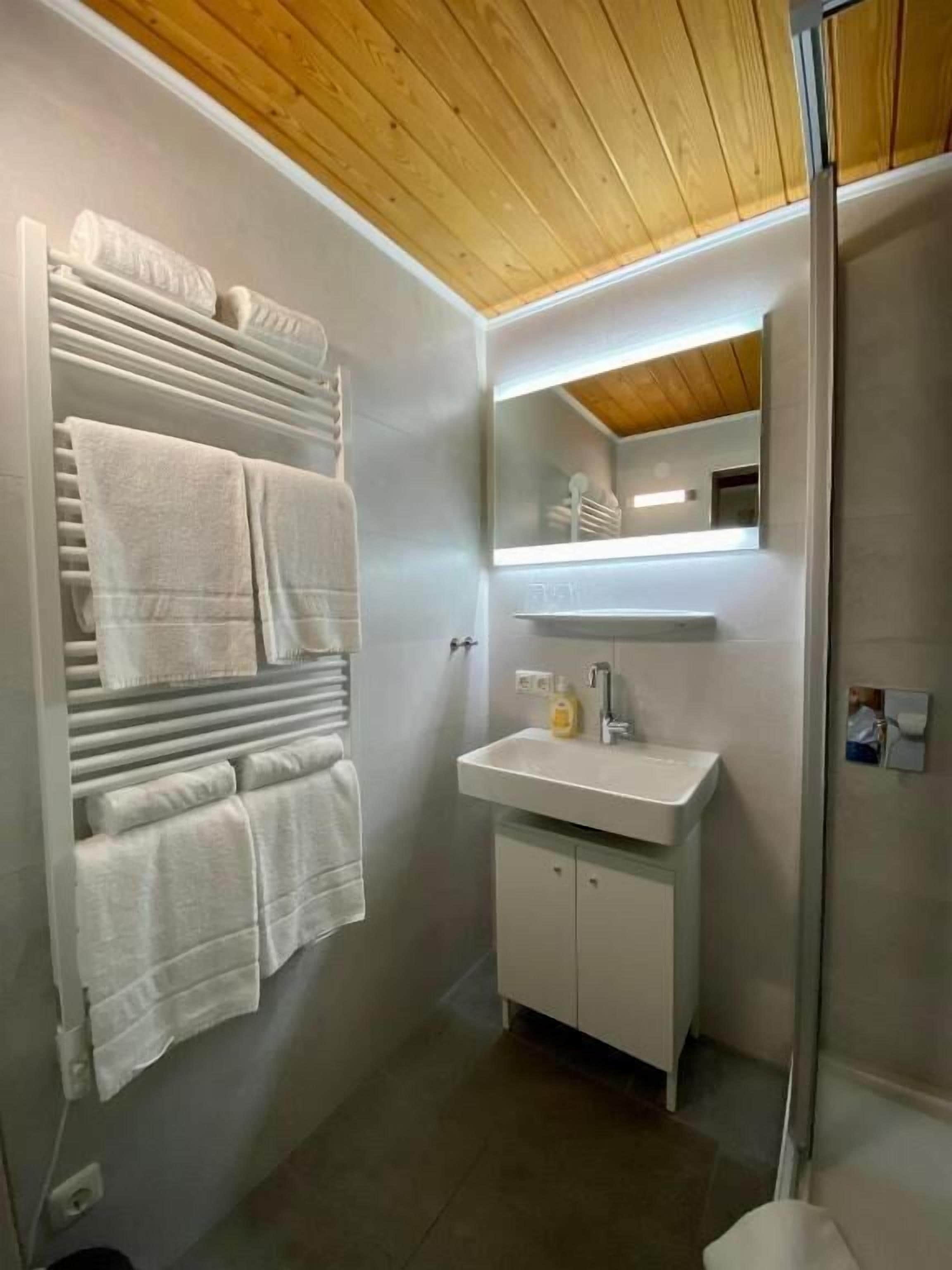 Ein modernes Badezimmer mit integriertem Handtuchhalter, einem weißen Waschbecken und einem Spiegel darüber.