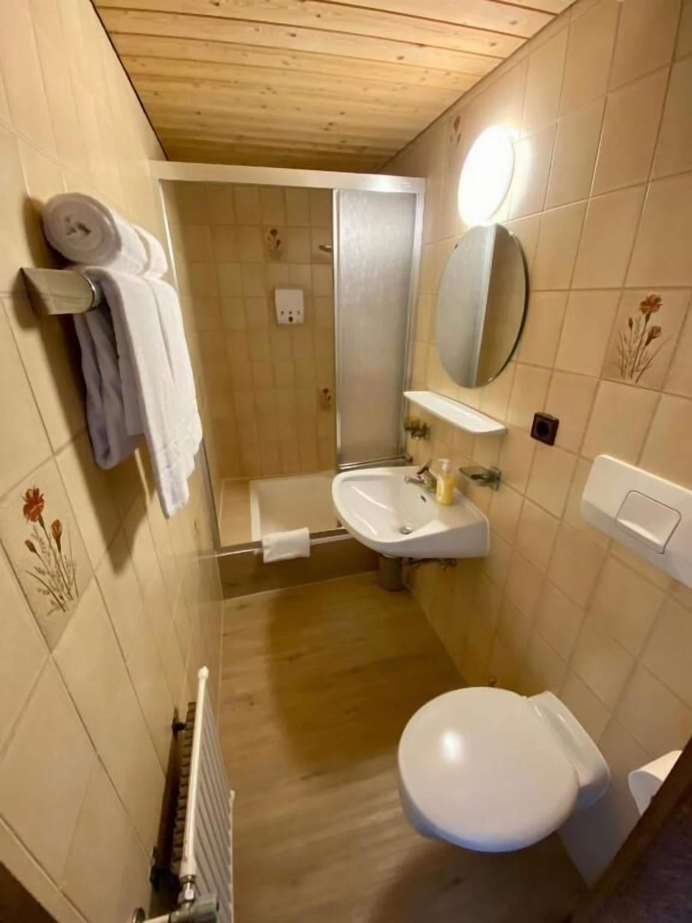 Ein kleines Badezimmer mit Toilette, Waschbecken und Dusche.