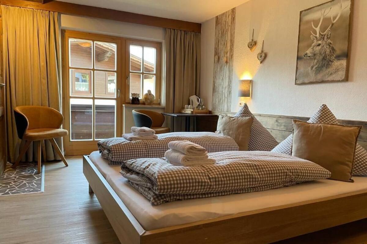 A hotel room with a large bed, a desk, a chair, and a window with curtains.