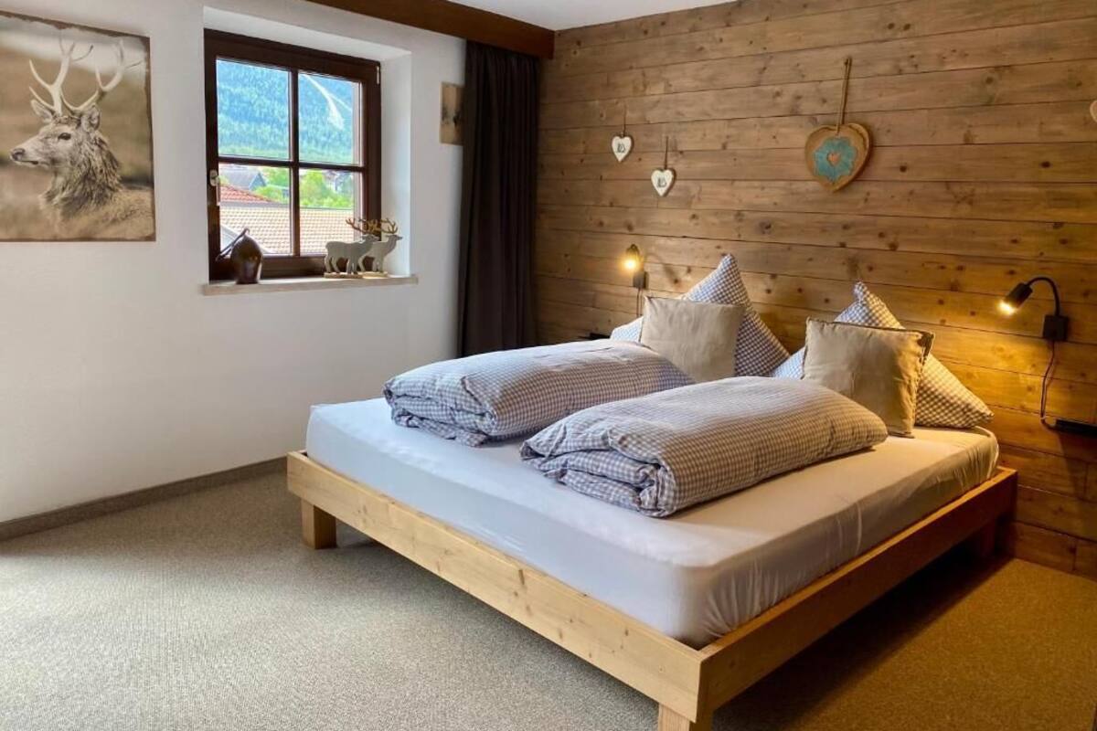 A bedroom with a wooden bed, a window with a view, and decorative wall elements.