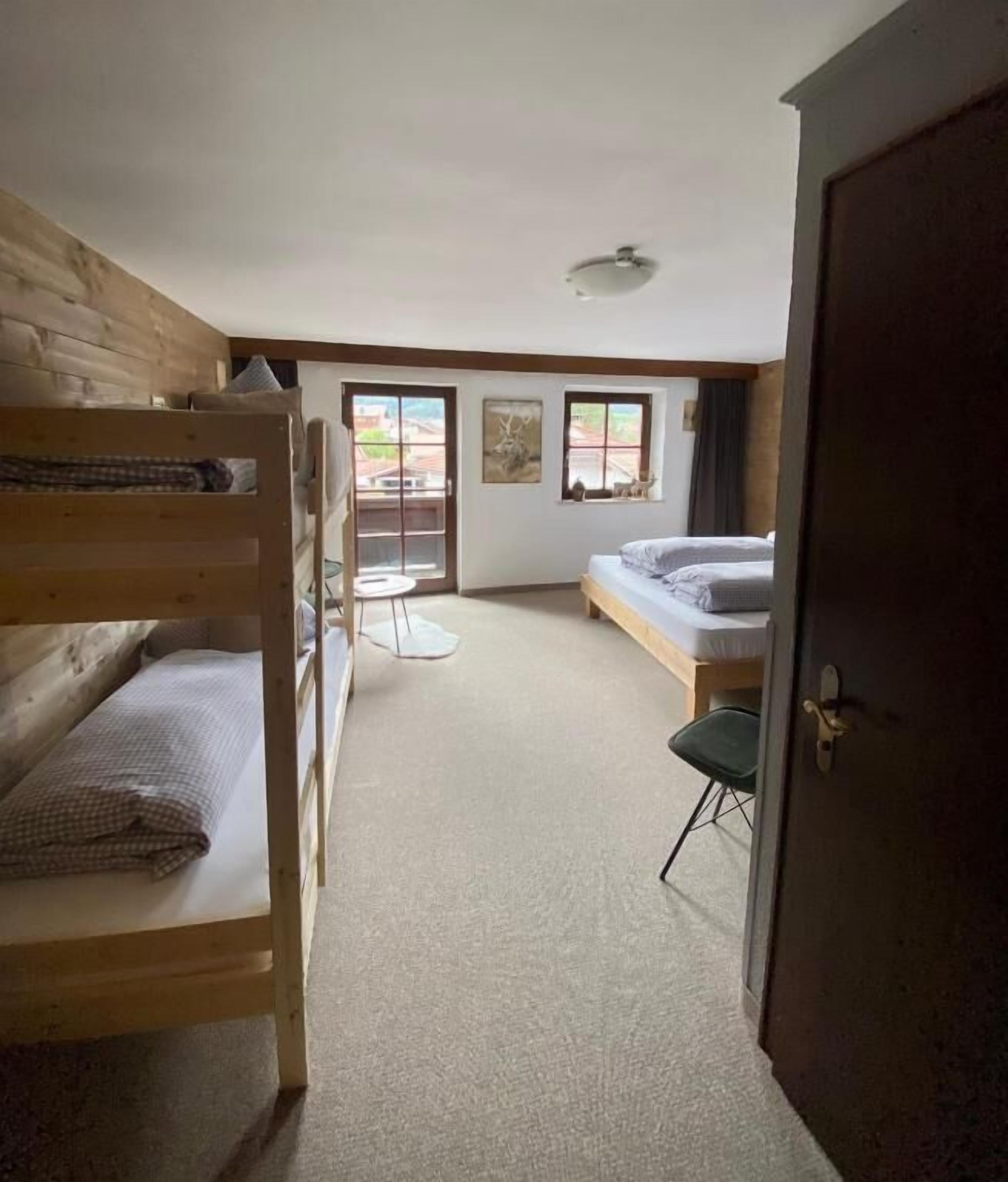 Een kamer met stapelbedden, een klein tafeltje, een bank en een deur.