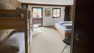 Een kamer met stapelbedden, een klein tafeltje, een bank en een deur.