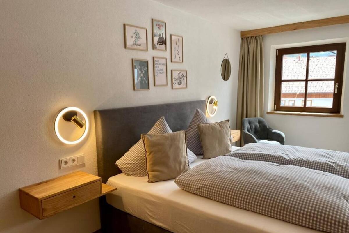 A bedroom with a bed, bedside tables, wall-mounted light, and framed pictures.