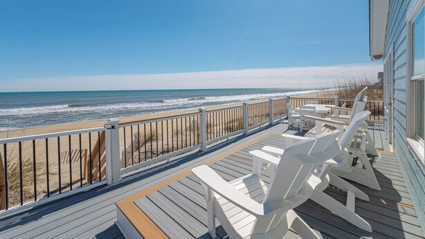 A wooden deck with white chairs, a railing, and a view of the ocean. - JL #838 | Deja View | Oceanfront | Ocean Views (Kill Devil Hills)