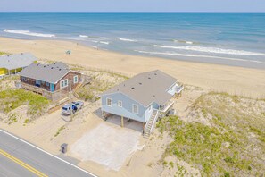 Una casa de playa con porche delantero, garaje y entrada para vehículos.