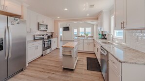 A modern kitchen with white cabinetry, stainless steel appliances, and a central island. - JL #838 | Deja View | Oceanfront | Ocean Views (Kill Devil Hills)