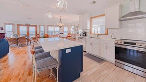 A spacious kitchen with a large island, modern appliances, and a view to the outside. - JL #261 | The Beach House | Oceanfront | Ocean Views (South Nags Head)