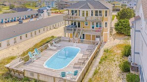 A multi-story building with a pool area, outdoor seating, and a view of the surrounding neighborhood. - JL #261 | The Beach House | Oceanfront | Ocean Views (South Nags Head)