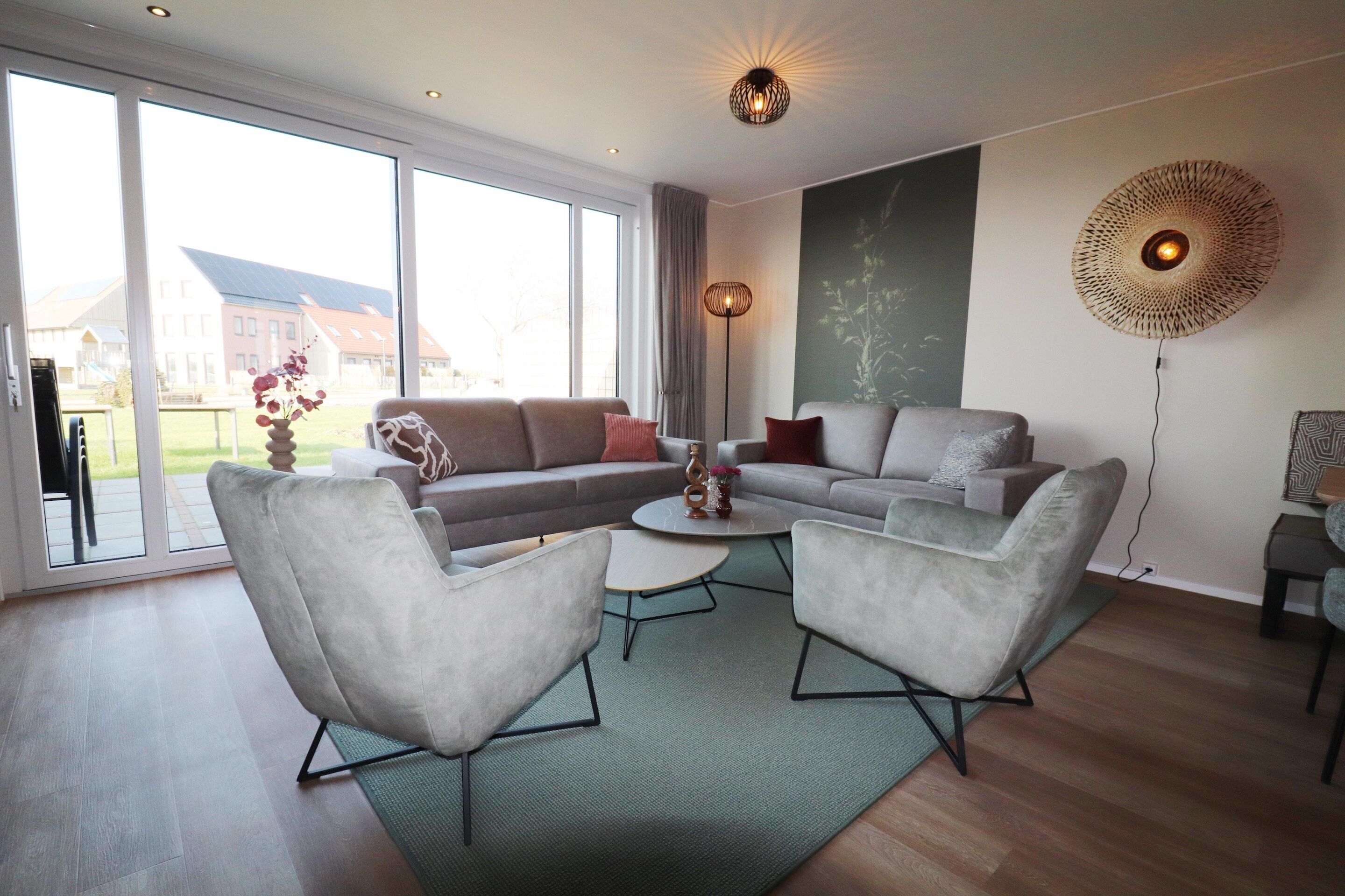 A modern living room with a sofa set, two armchairs, a coffee table, and a floor lamp.