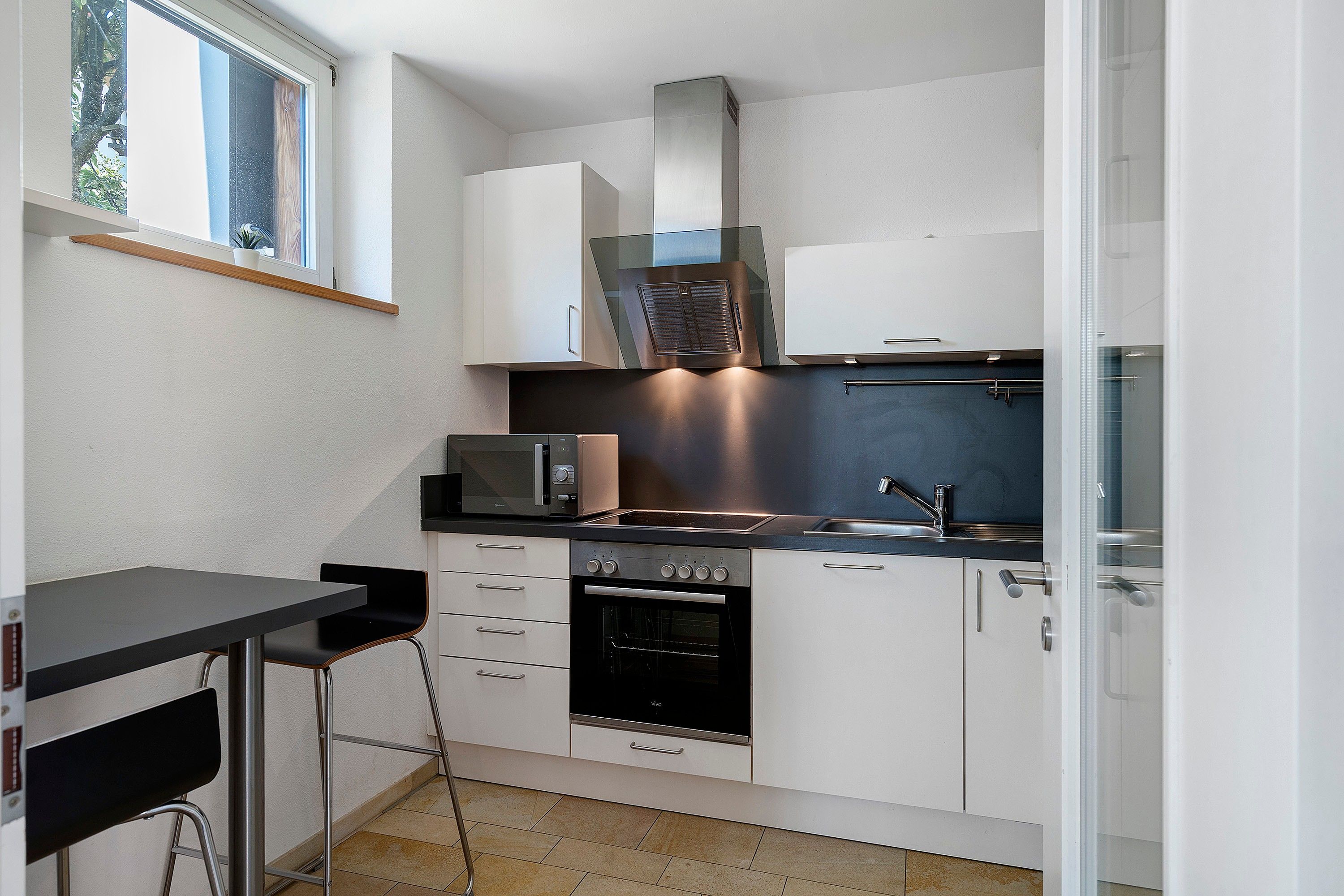 A compact kitchen with a microwave, oven, and a small dining area with a table and chair.
