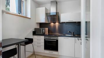 A compact kitchen with a microwave, oven, and a small dining area with a table and chair.