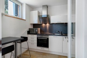 Eine kompakte Küche mit Mikrowelle, Backofen und einer kleinen Essecke mit Tisch und Stuhl.