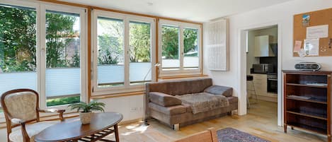 A room with a dining table, chairs, a sofa, a coffee table, and a rug. There is a kitchen area with a microwave and a cabinet.
