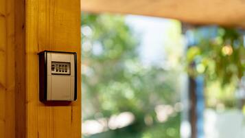 A security keypad mounted on a wooden post, with a blurred green outdoor background.