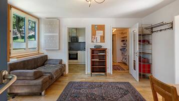 Een woonkamer met een bank, een vloerkleed en een keuken op de achtergrond.