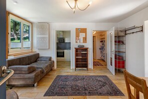 A living room with a sofa, a rug, and a kitchen in the background. - Atelierwohnung nahe München im Zentrum von Pfaffenhofen/Ilm (Pfaffenhofen an der Ilm)