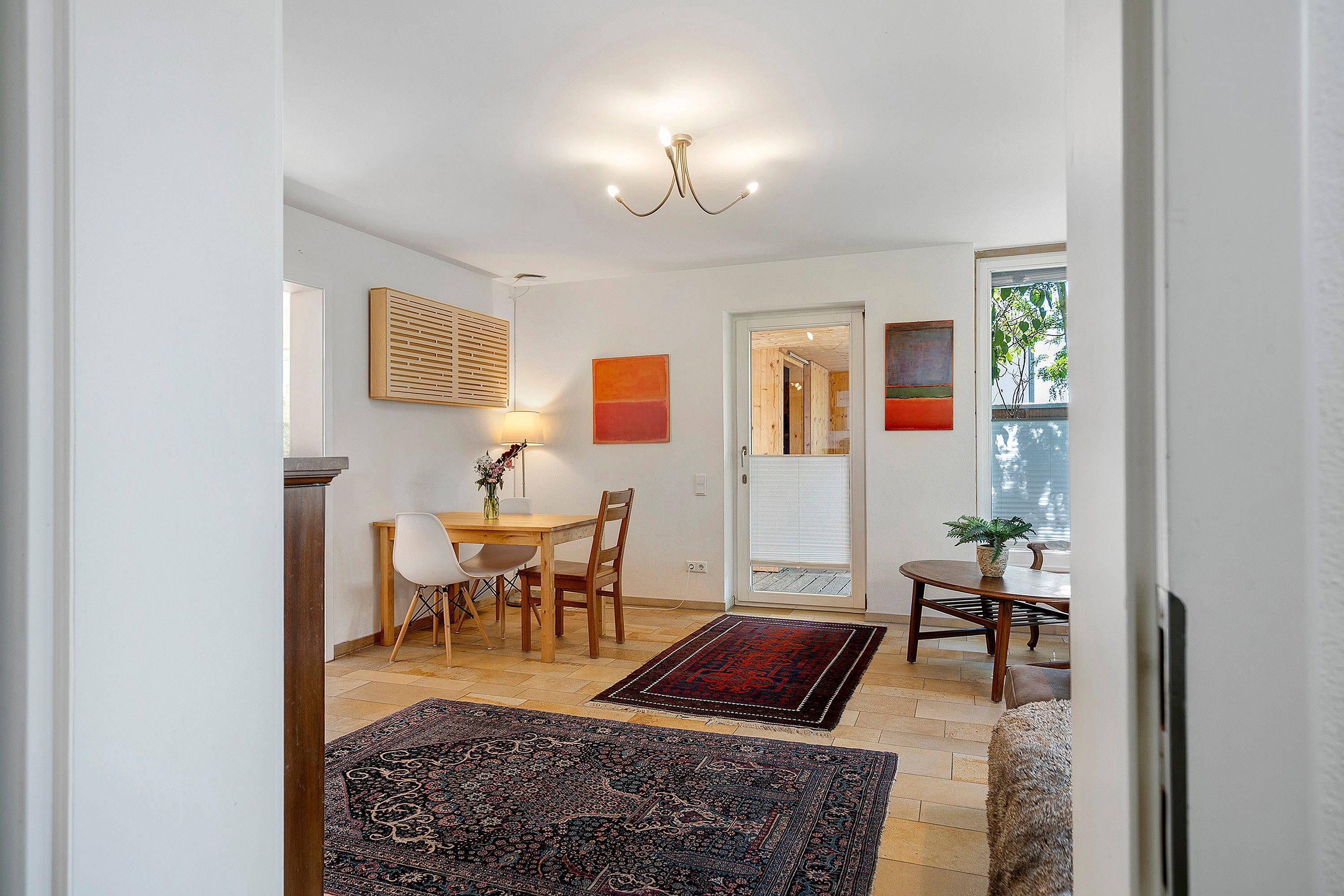 A dining area with a table and chairs, a lamp, and a rug.