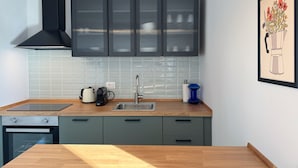 Eine moderne Küche mit grauen Schränken, einer schwarzen Dunstabzugshaube, einer Edelstahlspüle und einer Holzausziehtafel.