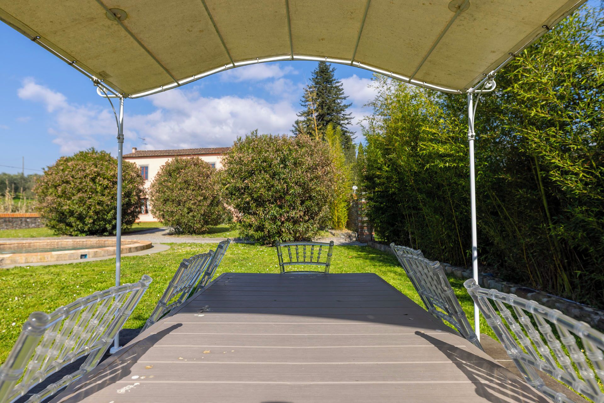 A covered outdoor area with a wooden deck, metal railings, and a bench.