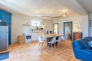 Cozinha compacta com área de refeições, um sofá azul e decoração rústica no teto.