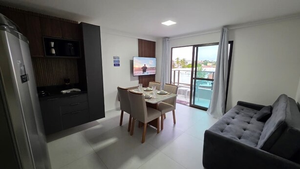 Ein modernes Hotelzimmer mit Essbereich, einer Couch, einem Fernseher und einem Balkon mit Blick.
