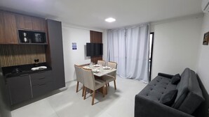 Ein modernes Hotelzimmer mit Essbereich, Küchenzeile, Flachbildfernseher und einer Couch.