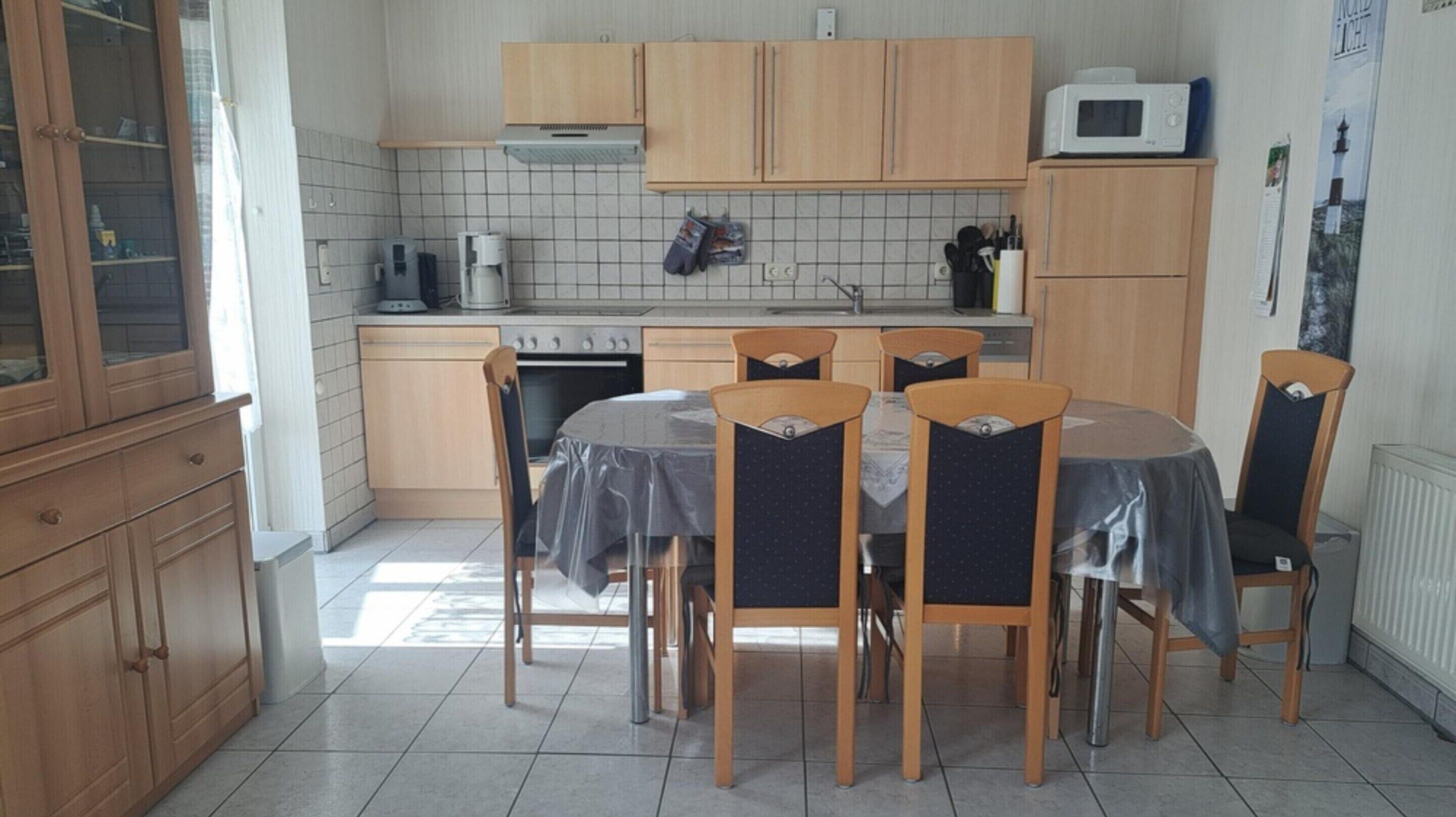 Una cucina con mobili in legno, un fornello, un forno a microonde e un tavolo da pranzo con sedie.