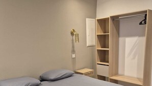 Ett sovrum med en säng, kuddar, ett sängbord, en garderob och en väggmonterad lampa.