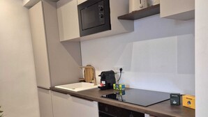 Ett modernt kök med vita skåp, en inbyggd mikrovågsugn, en brödrost och en diskmaskin.