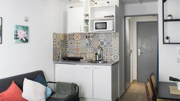 Een knus woongedeelte met een kitchenette, een eethoek en een bank met kussens.