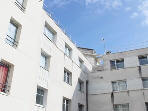 Ein mehrgeschossiges Gebäude mit Balkonen, großen Fenstern und blauem Himmel.
