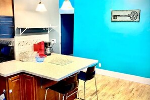 Een keuken met een wit aanrecht, houten kastjes en een blauwe wand.