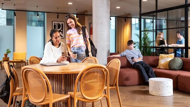 Ein modernes Interieur mit einem runden Holztisch, Korbstühlen, einem roten Sofa und einem weißen Couchtisch.