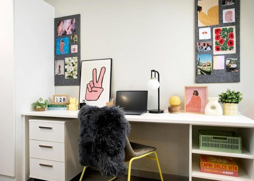 Un bureau moderne, avec un ordinateur portable, un cadre représentant un symbole de paix et divers objets personnels.