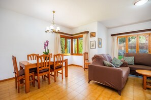 Un coin repas avec des chaises et une table en bois, un canapé marron et un lustre.