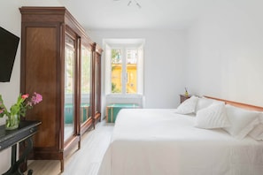 A bedroom with a bed, a wooden wardrobe, a bedside table, a window, and a view of the outside. - Marmorata 169 - Loft in Testaccio (Rome)