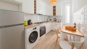 A compact kitchen with a washing machine, a microwave, and a dining area with a table and chairs. - Marmorata 169 - Loft in Testaccio (Rome)