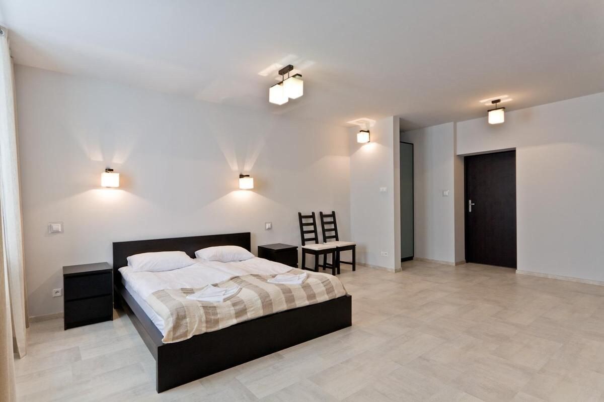 Un dormitorio con cama, mesitas de noche e iluminación en la pared.