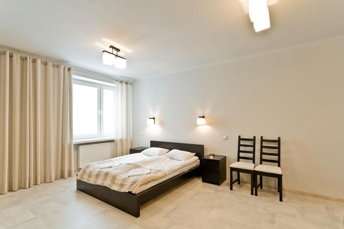 A bedroom with a bed, nightstands, and a chair.