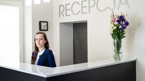 A reception desk with a clock and a sign that reads 'RECEPCJA'.