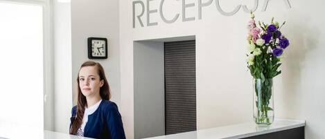 A reception desk with a clock and a sign that reads 'RECEPCJA'.
