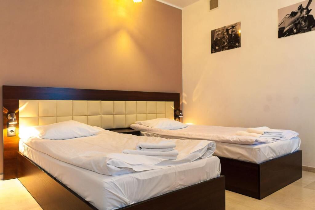 A hotel room with two beds, a wooden headboard, and a wall-mounted light fixture.